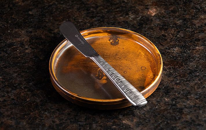 Buttermesser auf einer kleinen runden Schale mit bernsteinfarbenem Inhalt