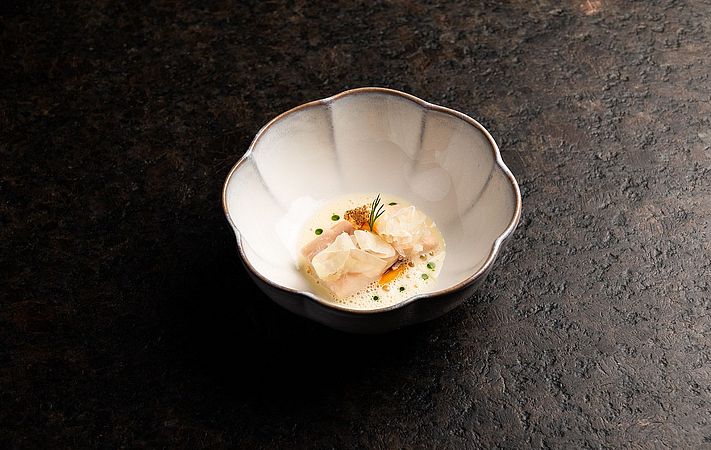 Fischstücke in heller Schaumsauce mit Kräutern in weißer Schale