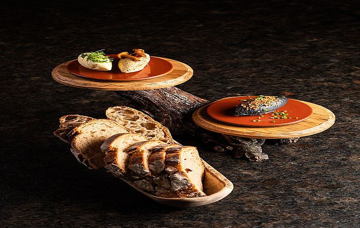Häppchen auf zwei Holzscheiben und Brotschale mit geschnittenem Brot