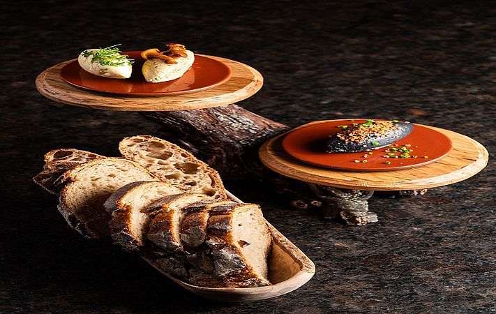 Häppchen auf zwei Holzscheiben und Brotschale mit geschnittenem Brot